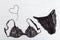 Beautiful silk lace bra and panty for woman. Black fashionable lingerie set and figure of heart from thin chain.