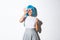 Beautiful silly asian girl in blue anime wig smiling happy, showing macaroon, standing over white background