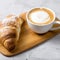 Beautiful and simple traditional French breakfast of fresh croissant and a cup of cappuccino