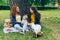 Beautiful sisters talking stroking dog sitting on lawn in park enjoying summer