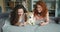 Beautiful sisters using smartphone and petting cute doggy lying on couch at home