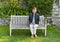 Beautiful sixty-five year-old female Korean tourist on a wooden bench in the Garden of the Villa Cipressi in Varenna.