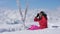 A Beautiful Skier Sits In The Snow And Puts On Her Goggles