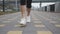 Beautiful skinny fit woman legs intense running on promenade in industrial part of city. Female sports athlete in white footwear d
