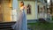 Beautiful skinny upset girl in silver and blue dress and in high heeled shoes poses standing on stairs of wooden house