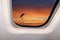 Beautiful sky landscape of red sunset with clouds and a flying paratrooper in the sky behind the porthole of a plane, a concept of