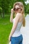 Beautiful slender athletic young girl in sunglasses in jeans and sneakers gleet in the Park summer day