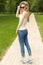 Beautiful slender athletic young girl in sunglasses in jeans and sneakers gleet in the Park summer day