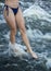 Beautiful slender naked legs of a girl in a bikini walking along the seething water of the river, ocean, sea