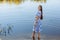 Beautiful slender woman in a long blue dress walks near the lake. Brown-haired girl with long hair walks in the water. natural