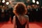 Beautiful Slender Woman In Open Back Dress Stands Backwards On The Red Carpet In Front Of The Paparazzi. Generative AI