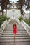 Beautiful slim brunette girl model in red dress posing on Staircase in Birth of our Lady Church, Montenegro
