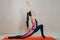 Beautiful slim fit woman coach stands in asanas on a bright rug on a beige background. Yoga practice. Useful hobby for maintaining