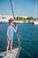 Beautiful slim little caucasian girl in sunglasses and striped sailor shirt standing on board of white yacht in sea port during