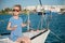 Beautiful slim little girl in a striped t-shirt and sunglasses sitting on board of luxury white yacht in summer cruise