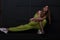 Beautiful slim model of a young woman in a stylish light green sports suit in a shoes is engaged in fitness near the vintage black