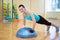 Beautiful slim woman doing push ups with bosu ball in gym