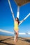 Beautiful slim woman in a yellow swimsuit is standing and posing near the wooden rescue tower on the sea coast