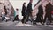 Beautiful slow motion shot of people`s legs and feet walking across a busy old city street with tram rails in the middle