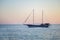Beautiful small pleasure cruise ship with masts sailing at sunset