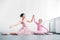 beautiful smiling adult and little ballerinas stretching and holding hands