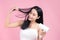 Beautiful Smiling Asian Girl With Black Long Straight Hair Using Hairdryer. Isolated on pink background