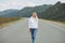 Beautiful smiling blonde young woman traveler in white hoodie on road, trip to the mountains, Altai
