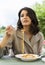 Beautiful smiling brunette girl having lunch in a street cafe, sitting at a table and eating Italian pasta. Advertising,