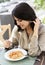 Beautiful smiling brunette girl having lunch in a street cafe, sitting at a table and eating Italian pasta. Advertising,