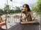 Beautiful smiling brunette girl is relaxing in a street cafe, sitting at a table and drinking coffee. Advertising, commercial