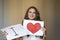 Beautiful smiling brunette woman holding two white cards with i love you words and red heart. Cute portrait for valentines day