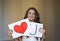 Beautiful smiling brunette woman holding two white cards with i love you words and red heart. Cute portrait for valentines day