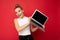 beautiful smiling fascinating happy blond young woman with gathered hair looking at camera holding computer laptop