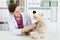 Beautiful smiling female doctor in white coat examine teddy bear