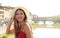 Beautiful smiling girl in Florence with Ponte Vecchio bridge and Arno river on the background. Portrait of young woman with hat