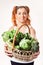 Beautiful smiling girl holding basket of fresh raw green vegetables isolated.