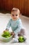 Beautiful smiling girl is sitting on a white plaid with plastic container with green apples