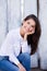 Beautiful smiling girl wearing blank white shirt and jeans posing against street wooden wall. Minimalist urban clothing