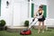 Beautiful smiling housemaid mows lawn by mower