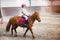 beautiful smiling little girl on her pony taking a riding lesson