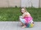 Beautiful smiling little girl in summer dress and bare feet sitting on beach ball on sidewalk