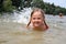 A beautiful smiling little girl swimming in the river with splas