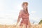 Beautiful smiling magnetic young woman having walk in sunny day, being at wheat field, touching stalks with hands, feeling rest,