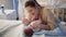 Beautiful smiling mother massaging and looking at her little baby son lying on bed at night. Happy parenting and family