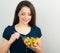 Beautiful smiling positive woman eating healthy organic vegatable salad on blue background. Closeup