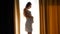 Beautiful smiling pregnant woman standing at big window and stroking her belly. Concept of happy pregnancy and baby