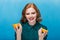 Beautiful smiling redhead girl photographed with fruit on a blue background.
