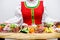 Beautiful smiling russian girl in folk costume stands near the buffet table and offers snacks.