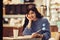 Beautiful smiling student woman reading a book in the cafe with warm cozy interior and drinking coffee