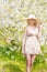 Beautiful smiling sweet girl with long blond curly hair wearing a hat with large fields in summer pink sundress